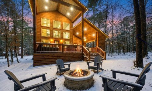 Broken Bow cabin with string lights and a fire pit on a snowy winter evening