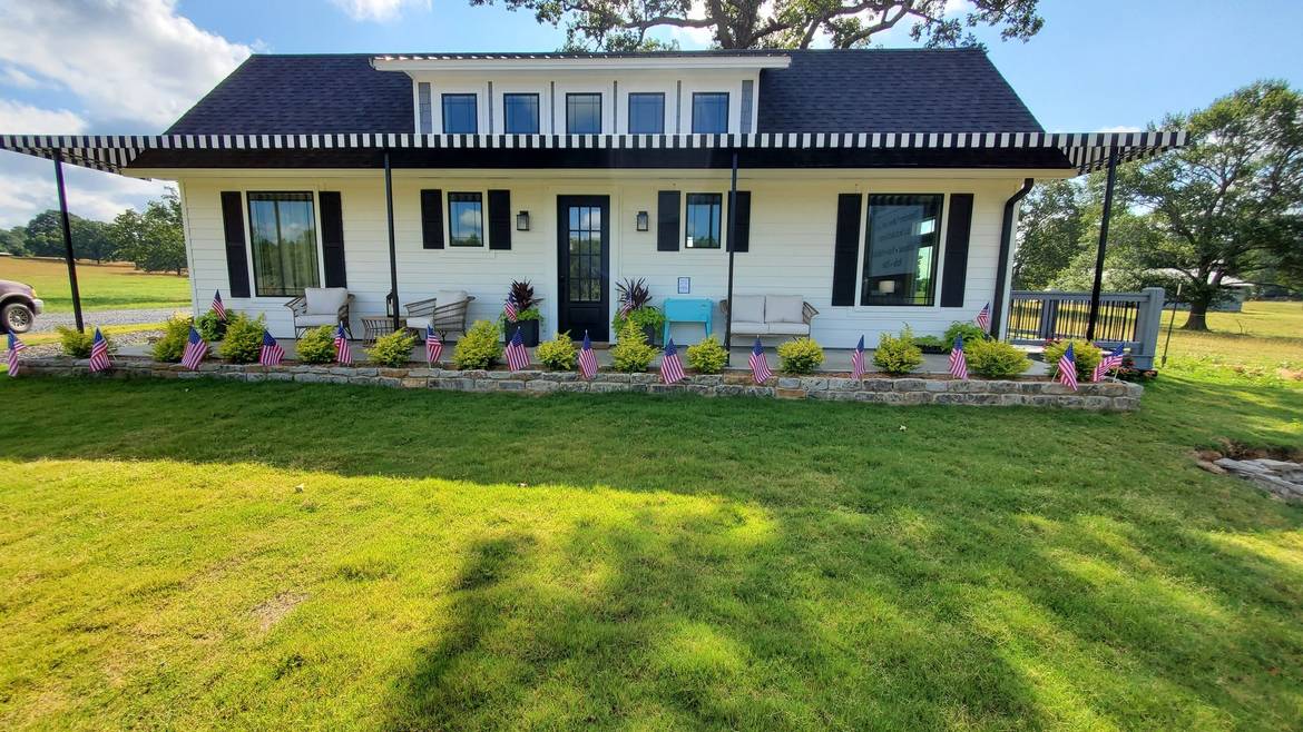 Building with a covered porch and flowerbeds at Three Creeks Reserve in Broken Bow